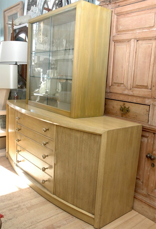 A painted cerused cabinet,  with tamboured doors and reeded interior in the style of Paul Frankl