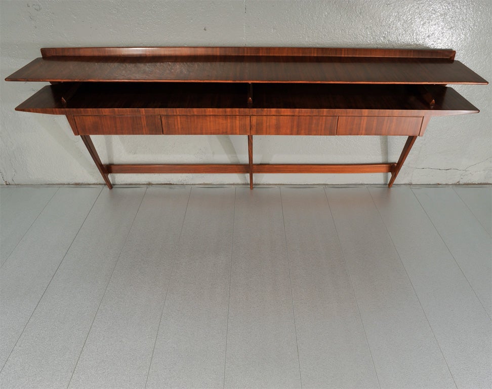 Produced by Spartaco Brugnoli, Cantú. Important console of rosewood veneer with gently beveled edges. Four drawers, floating shelf, and three architectural supports.  *To see our entire inventory, please visit www.donzella.com<br />
<br