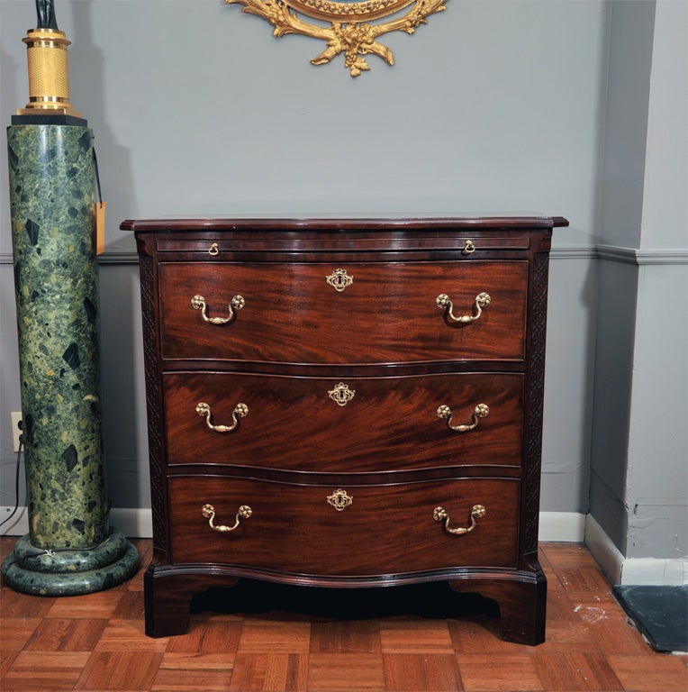 Late 18th century mahogany serpentine chest of drawers. The moulded top with outset corners above a leather covered brushing-slide, above three long drawers flanked by blinded fret carved corners on shaped bracket feet.