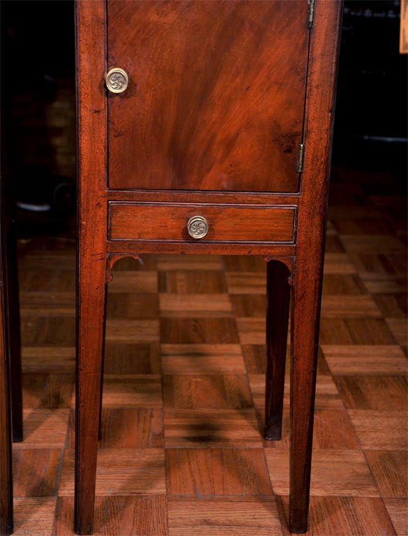 Pair of Georgian mahogany pot cupboards. Each with a galleried top, cabinet door and drawer, on square tapering legs with scrolled corner brackets. With original brass rosette handles.