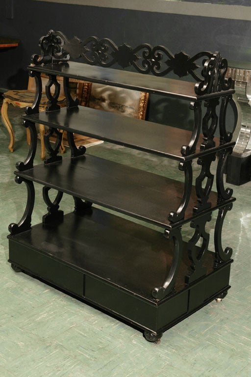 This English etagere in oak has been ebonized black to give it a stylish and masculine appeal. The carving is fine and the etagere has ample usable space for display or storage.Raised up on carved melon shaped feet it retains the original  inset