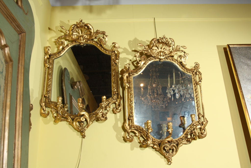 A good pair of gilt Rococo syle girondole mirrors elaborately carved with three candle supports on each one and carved shell and foliage motifs.