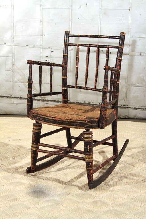 Wonderful carved faux bamboo and painted child's rocking chair with original rush seat. Retains original surfaces.