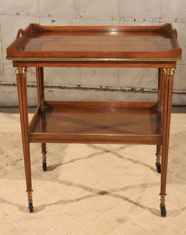 Chic vintage Baker Furniture Walnut Louis XVI style bar/serving cart with brass accents and original casters. Pull out slide trays at each end.