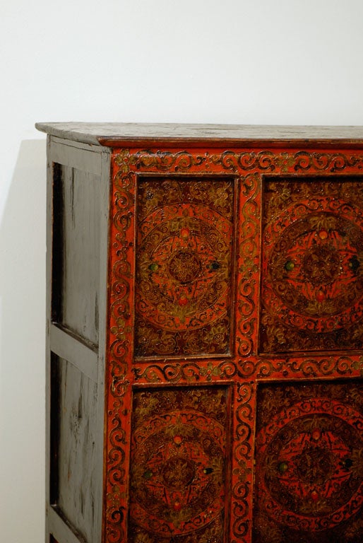 Tibetan Cabinet with 4 doors and original leather pulls.  A meaningful floral design borders the piece and a geometric motif has been painted into each panel on the front face.  Cabinets such as this were rare in Tibet until the early 19th century,