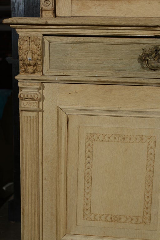 English limed oak library bookcase with three glazed doors over three drawers over four carved raised panel doors, resting on small bracket feet.This bookcase features upper and lower carved styles with carved lion heads and the top now fitted with