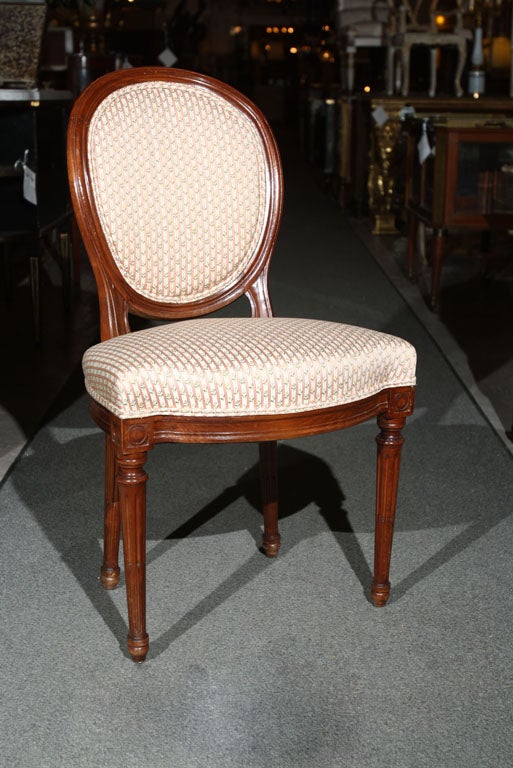 Set of four walnut French dining chairs, in the style of Louis XIV, circa 1930s, the oval padded back joint by cushioned seat, standing on turned fluted legs ending in toupie feet. Seat height 18 1/2