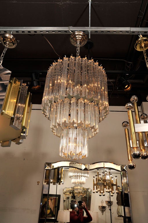 Elegant stylized crystal  chandelier<br />
with three tiers of prism crystals<br />
in varying lengths.  Has chrome<br />
fittings and is fitted with eight <br />
lights.  Height is 38