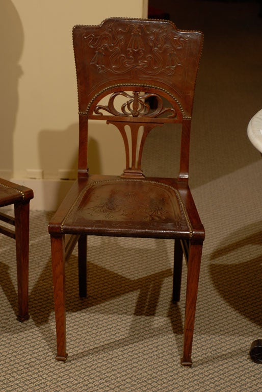 A lyrical set of six dining chairs from teh Art Nouveau period. The patination of both the leather and teh wood on this set of chairs is amazing. Art Nouveau designs typical to the period form each chair's hand-carved pierced splat and are tooled