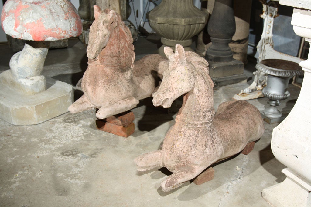 Wonderfully decorative pair of cast stone horses in opposing positions with studded collars and full manes.  Prick ears and a soft, warm expression make this pair a unique find.  Fabulous flanking a doorway or path or atop a stone wall as you enter