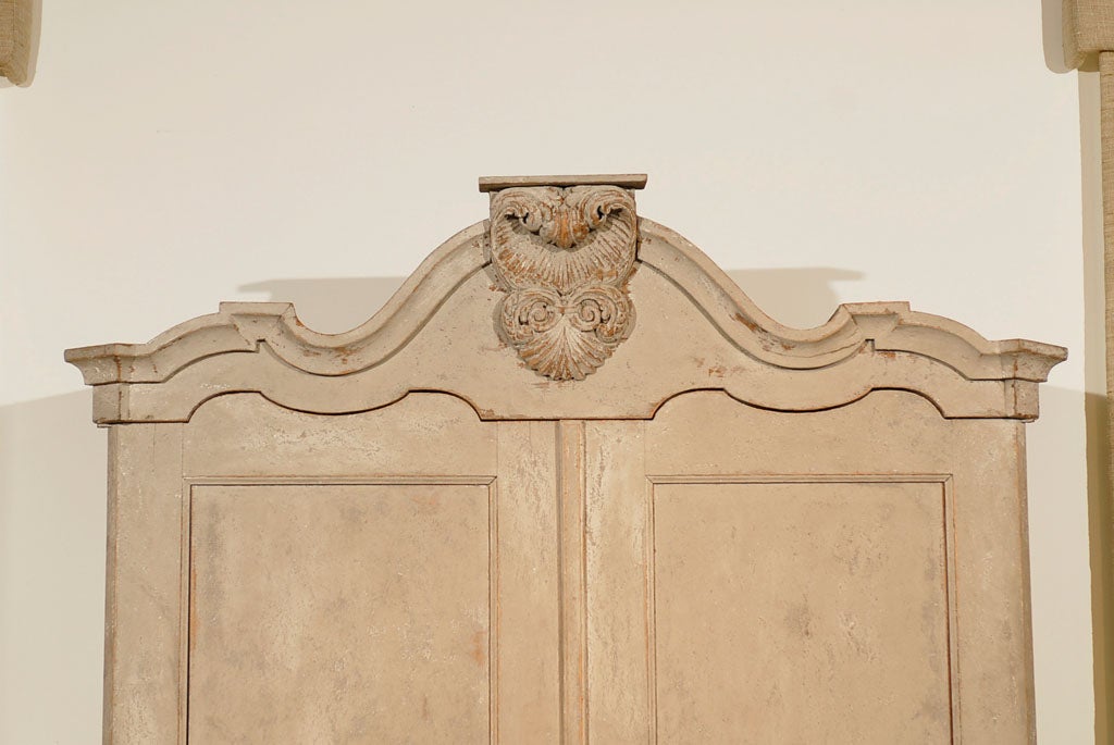 A Dutch Rococo painted linen press from the late 18th century, with carved crest, two doors and bombé chest. Created in the Netherlands during the last decade of the 18th century, this tall cabinet features a bonnet type cornice, accented with an