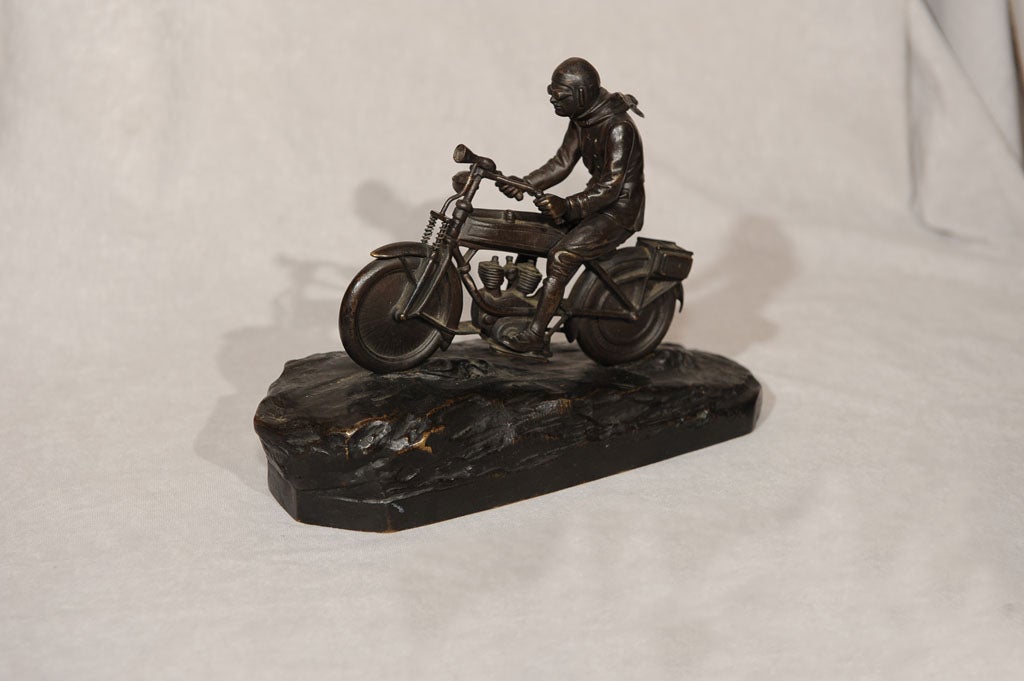 This extraordinarily rare bronze model depicting a young man on a motorcycle traveling up a road.  It's a subject that almost never comes up in vintage bronzes.  His goggles and his windblown scarf and the great detail of the motorcyle add great