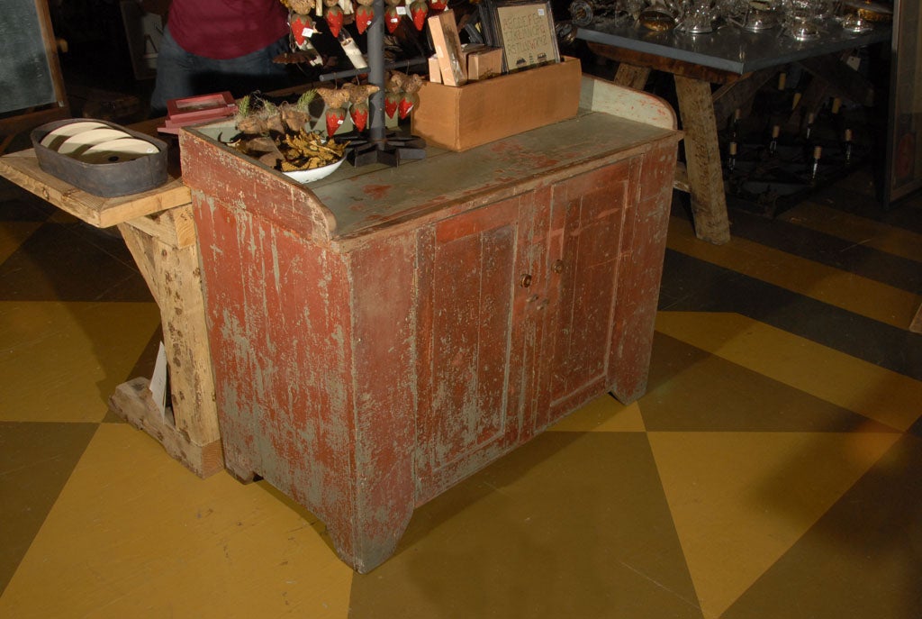 Charming painted wooden dry sink.  Has one internal shelf and wooden toggles on the door fronts.  Lovely glue/grey and red overpainted finish.