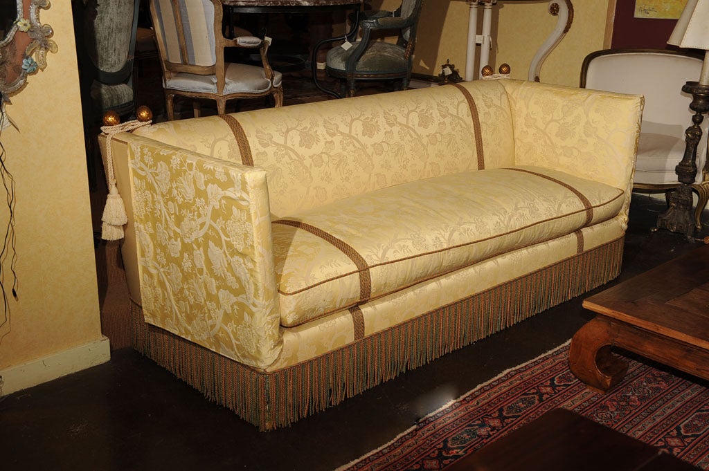A LONG KNOLE SOFA UPHOLSTERED IN YELLOW DAMASK, PASSEMENTERIE AND TASSELS.THE CARVED GILT FINIALS ARE ESPECIALLY BEAUTIFUL.THIS SOFA IS LONG, EXCEPTIONALLY PLUSH AND VERY COMFORTABLE.