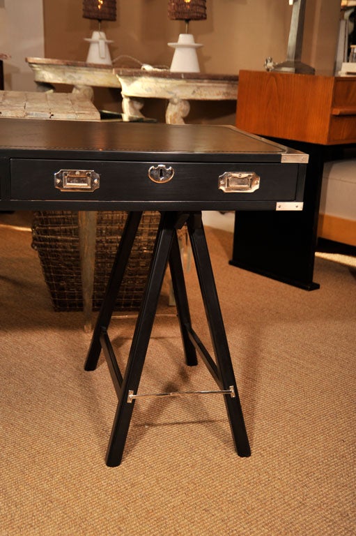Ebonized two-drawer campaign desk with nickel plated fittings on sawhorse legs