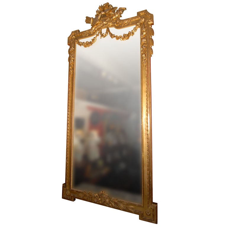 A handsome large French hall (portrait or pier) mirror featuring a carved giltwood frame.
Featuring a design in high relief of two birds perched on two quivers of arrows mounted on a lyre, surrounded by garlands of roses and laurel leaves, the