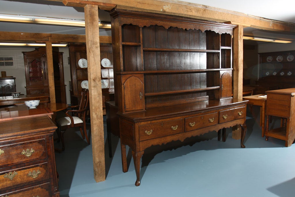 Welsh dresser in oak with three drawers, cabriole legs, scalloped apron and crown. Rack features two spice cabinets below double shelf storage flanking three thick shelves.