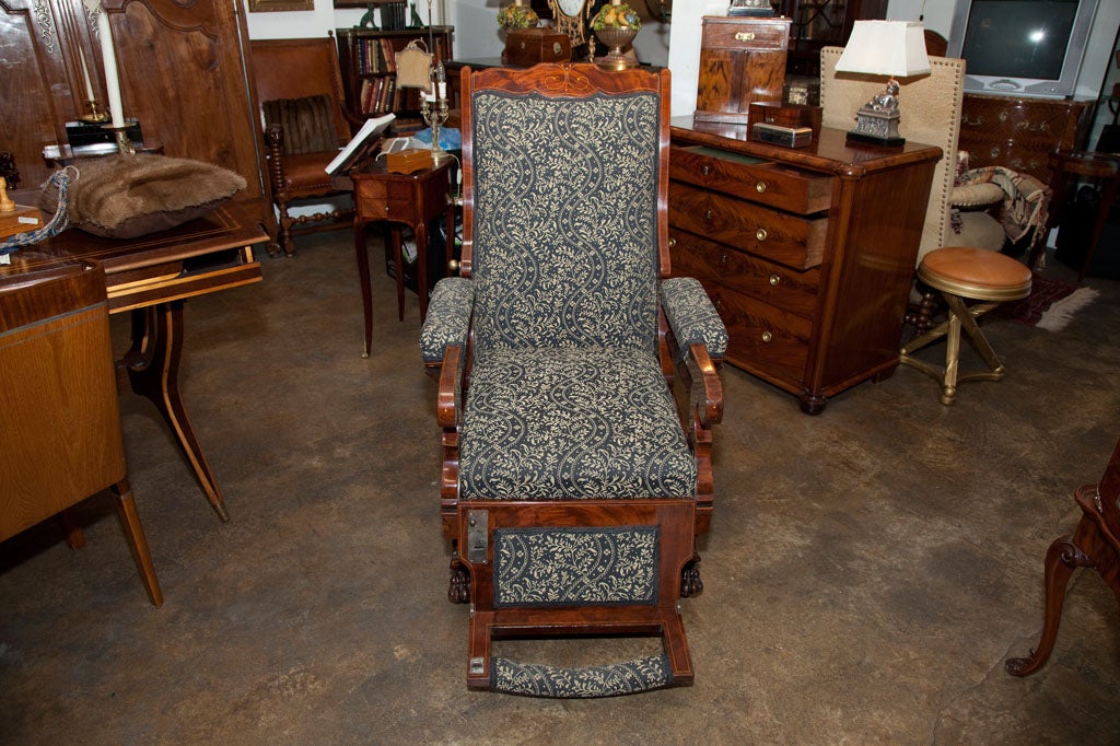 Rare 19th c., Flame Mahogany veneer Biedermeier library recliner  chair. Inlay scroll motif, attached foot rest and brass casters wheels.