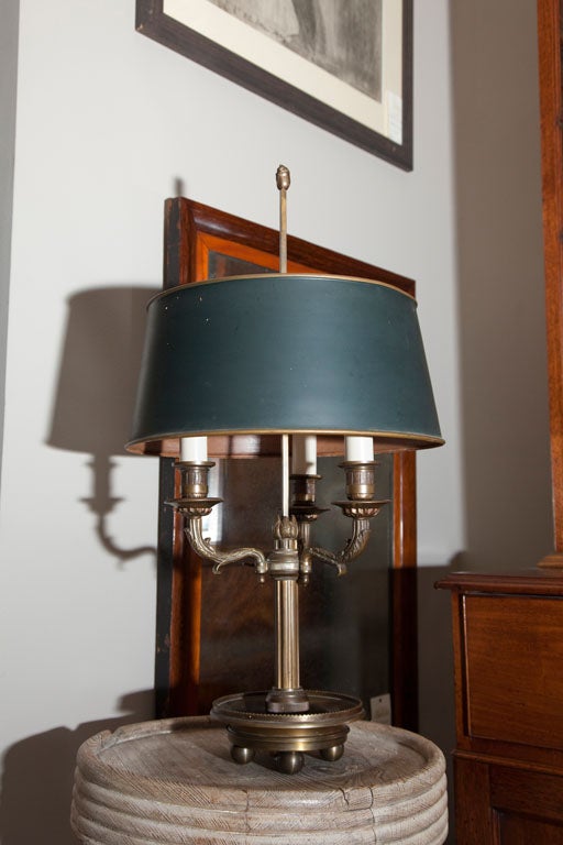 Late 19th-century French Bouillotte or candlestick lamp featuring three candlesticks with brackets and a black tole shade with brass rim. The brass base has three foliate arms that extend from a fluted column stem mounted upon a dish-shaped base