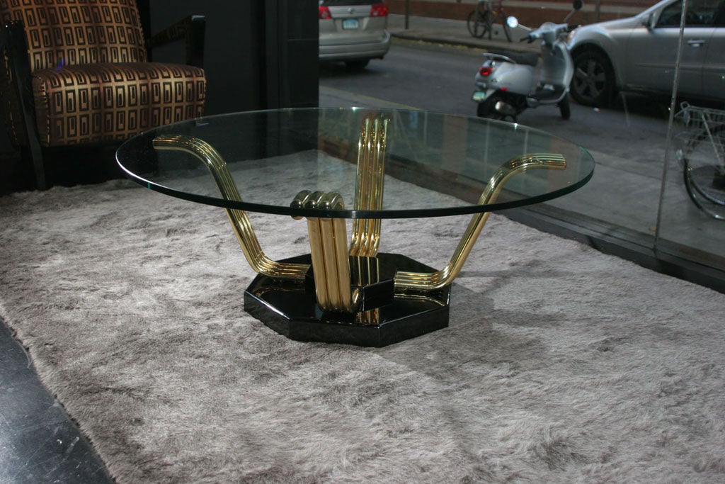 Four serpentine brass legs emerge from a black lacquered octagonal base to support a 42