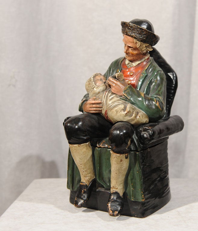 Warm and endearing example of a well detailed and painted terracotta humidor.  The elderly gentleman is bottle feeding the little baby as he rests in his favorite armchair.  A great subject indeed.  Terracotta humidors have become extremely