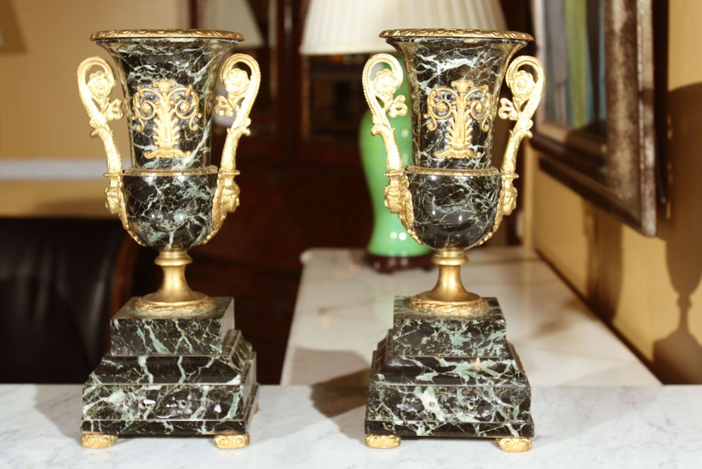 Pair of marble (possibly Malicite) urns, with ormolu decorations and handles, raised on square marble bases standing on ormolu feet.