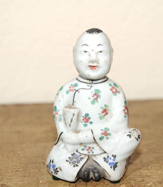 A Chinese porcelain figure of a young boy used for holding sticks of incense