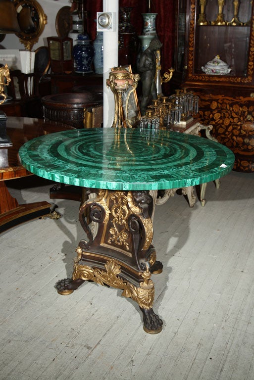 A SOLID  BRONZE  TABLE BASE, PATINATED AND GILDED, FEATURING GROTESQUE ANIMAL MASKS, PAW FEET, SCROLLS AND DECORATIVE ELEMENTS, TRIFOIL  FORM. <br />
A  42 INCH ROUND MALACHITE TABLE TOP , VENEERED IN CONCENTRIC  CIRCLES. THE TOP IS  NOW SOLD!!!<br
