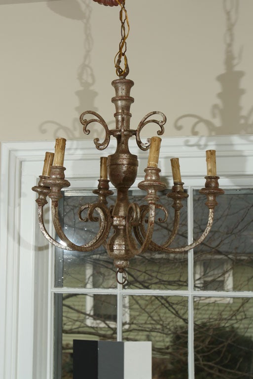 This elegant six-arm chandelier is fabricated from wood and iron and the perfect size for over a dining table for six. With its worn silver-leaf over underlying red paint patina, it lends an old-world elegance to any room and features its original