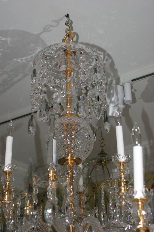 Custom-made Georgian style two-tier nine-light twelve-arm cut crystal chandelier, with a lobed canopy above a diamond cut ball stem with faceted serpentine arms alternating with spires above a lower canopy all with swags of crystal buttons and