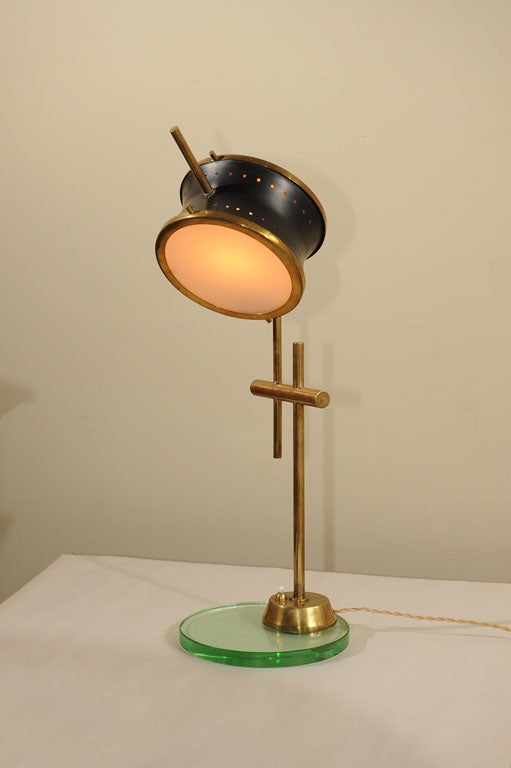 An adjustable drum form light source supported by brass rods on round glass base