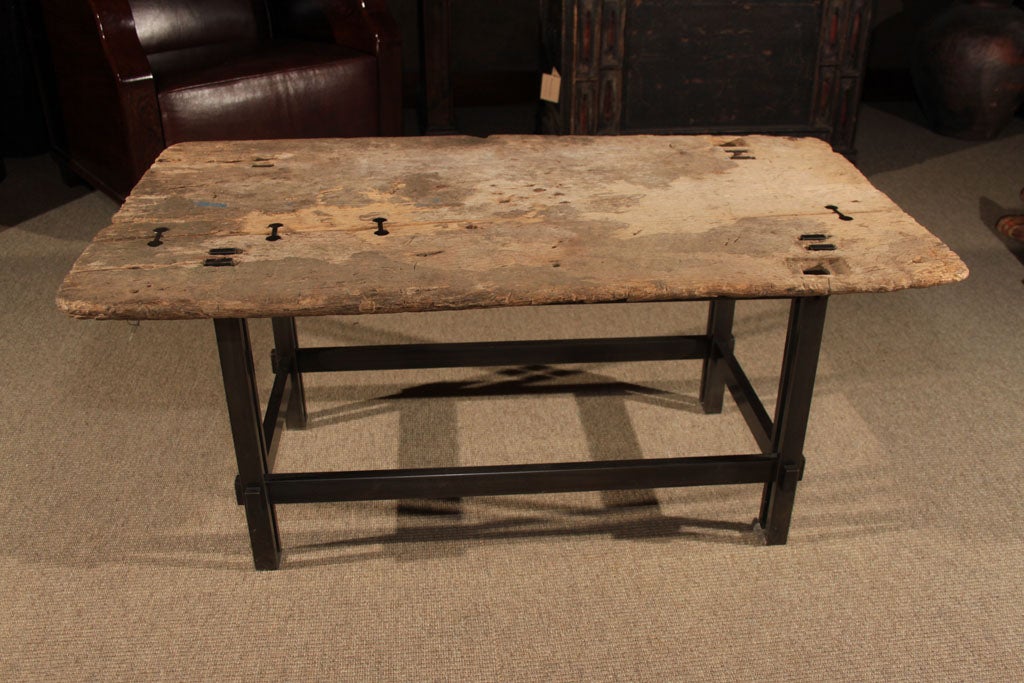 A Philippine molave wood table top on contemporary metal base. The heavily worn table top with extensive wear and patina from use, and original holes from where the tenons of the original base attached to the table. With contemporary metal