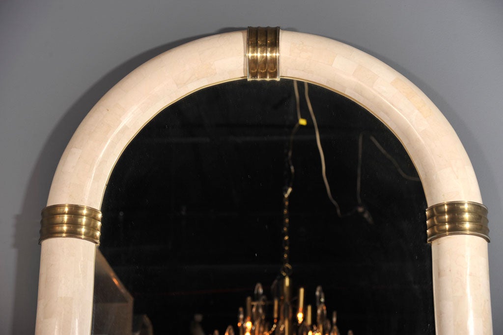 A pair of large mirrors in a racetrack form bullnose frame veneered with cream-colored stone and six bronze band appliqués. By Maitland-Smith, Ltd. Philippines, circa 1970.