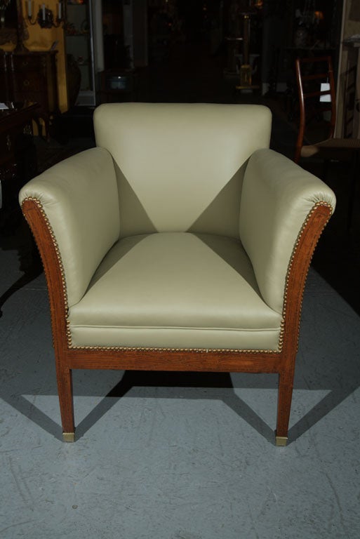 A pair of Vienna Secessionist armchairs newly upholstered in leather with nail head trim having an inlaid mahogany frame with square tapering legs ending on brass feet.