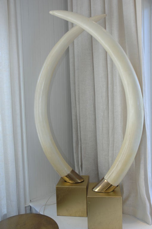 Large Resin Elephant tusks with brass fittings on a square metal platform.