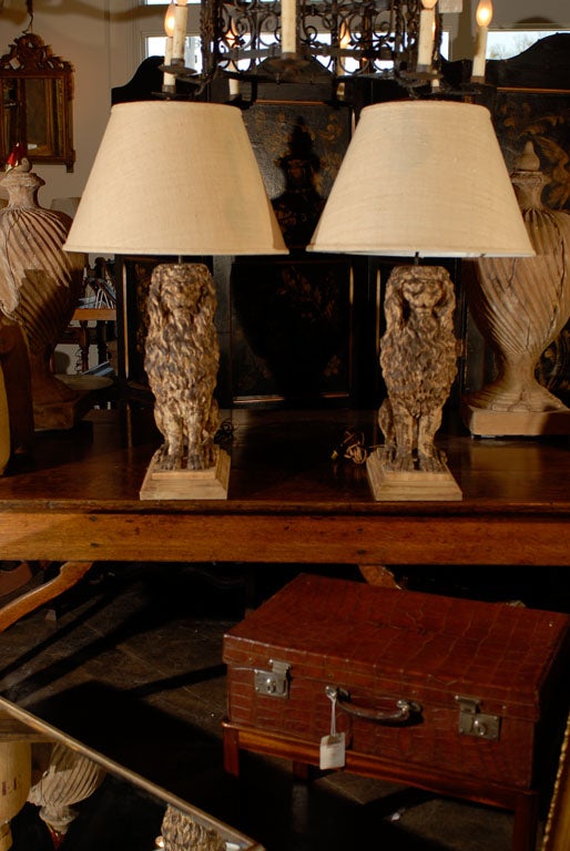 A pair of large Belgian carved wood lions from the 1880s made into table lamps with their shade. This late 19th century pair of table lamps each features a lion sitting proudly on a stepped base, propped on its front legs, the top of his head