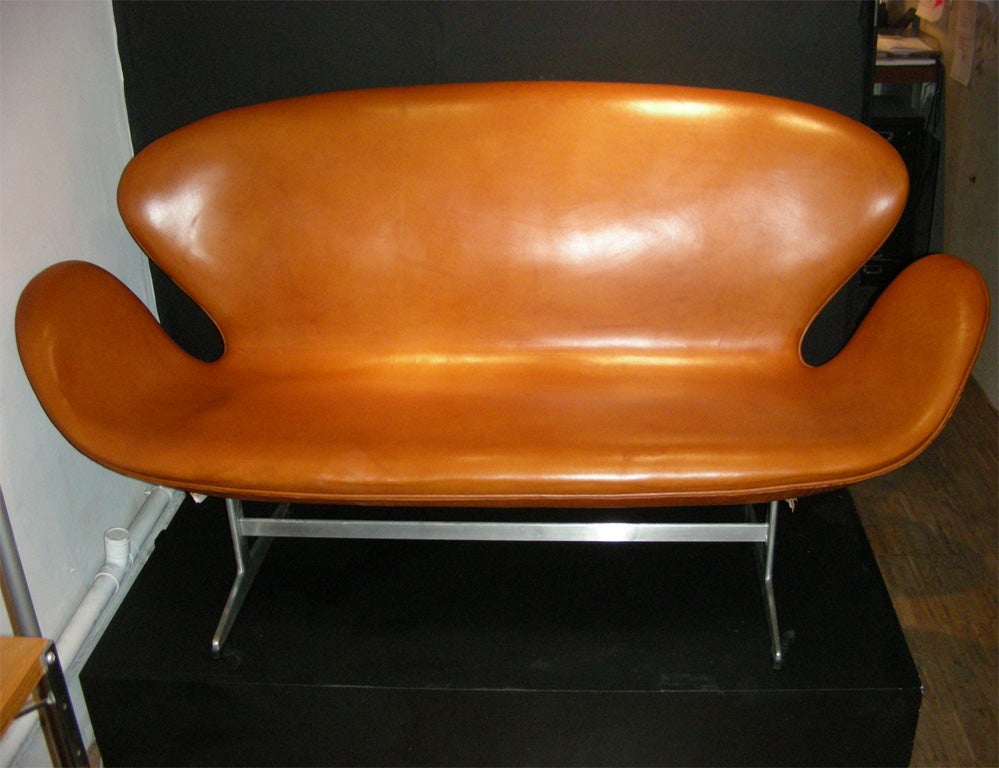 1960s settee by Arne Jacobsen with metal legs and tan leather upholstery.