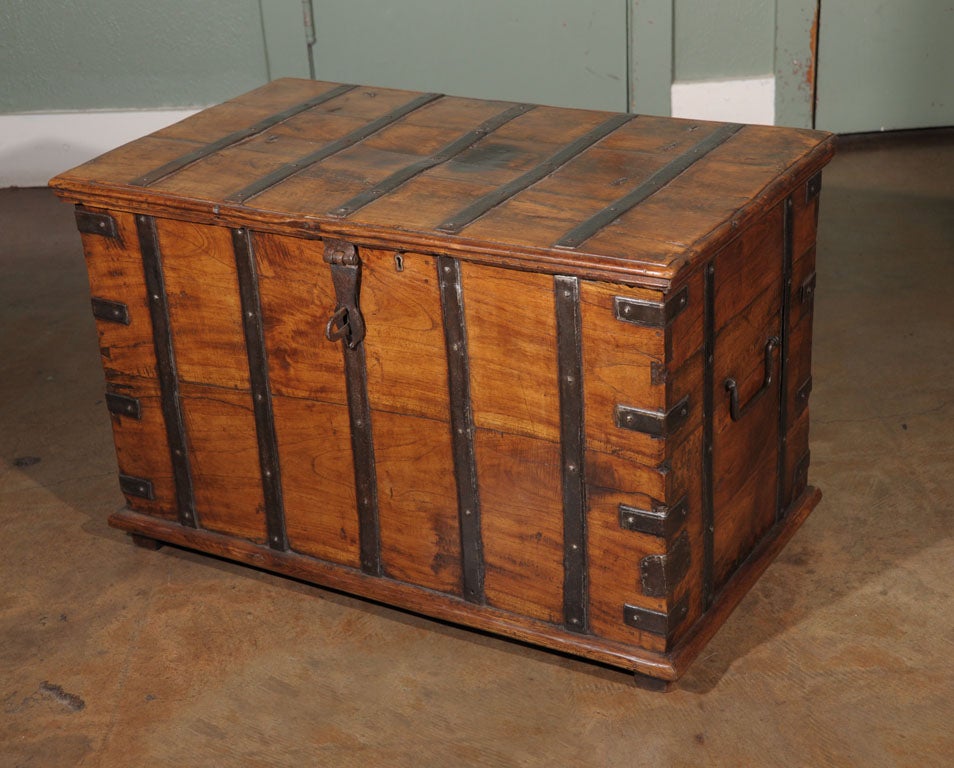 A handsome Campaign-era boarded chest bound in iron featuring a hinged lid with iron clasp, iron handles, an interior with a hinged-lid tool box, and resting on wooden rails.<br />
<br />
Campaign-era trunks and coffers were the travel items of