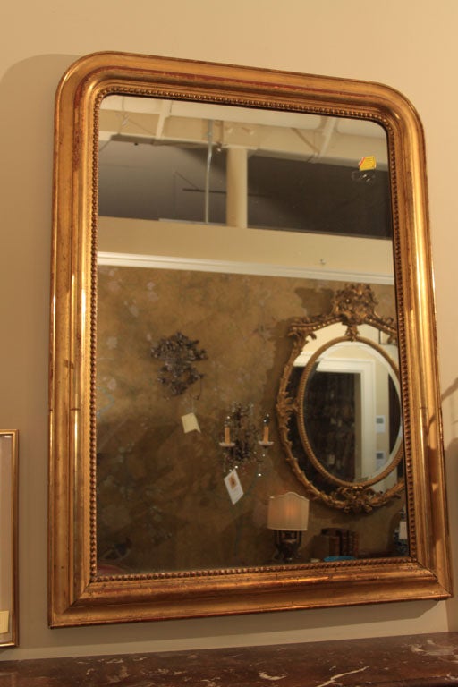 Beautifully gilded Louis Philippe mirror with original mercury glass.  The glass has wonderful foxing through out and the glass sparkles with the mercury.  Beautiful patina on the gilding and an original old wood back.