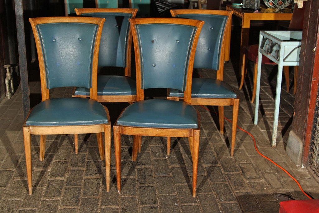 Set of four high back French dining chairs with medium wood colored frames in original blue vinyl upholstery. Frames are sturdy. Some buttons are missing.