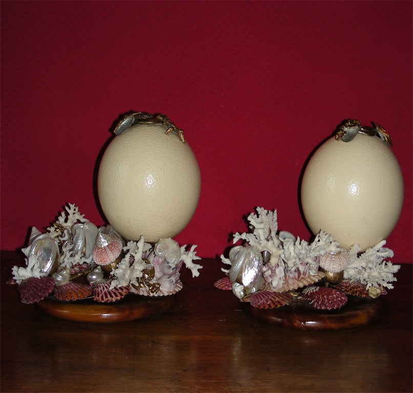 Two 1998 candleholders by Frédérique Lombard Morel made of an egg set on a wooden base, decorated with multicolored shells and gilt metal elements.