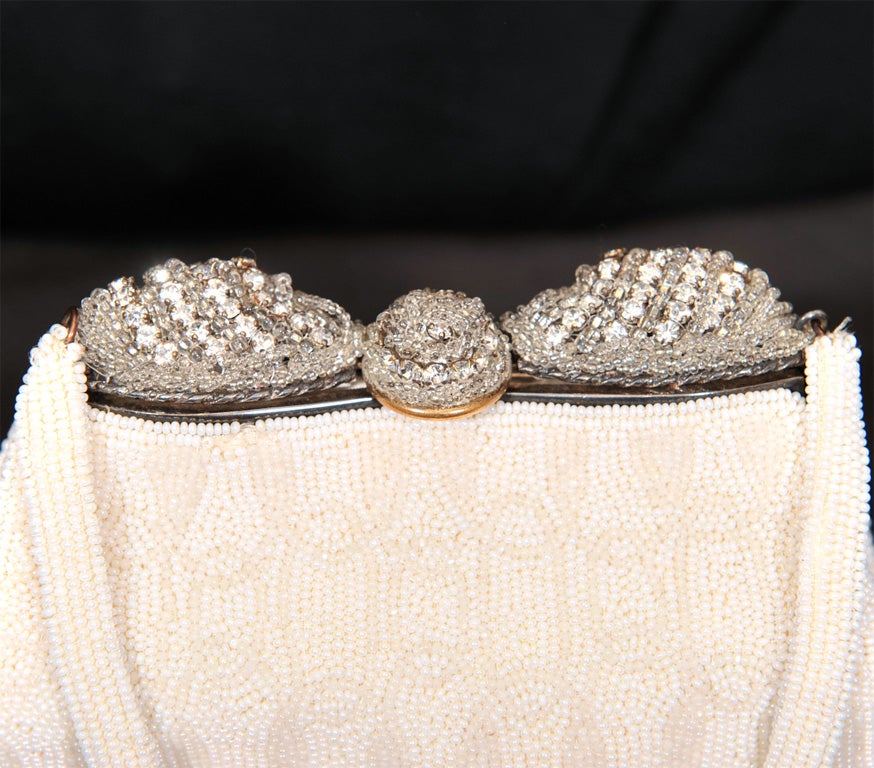 White on white beaded evening bag with rhinestone and clear beaded frame made in France circa 1950's. Some of the white beads have a glimmer to them making the bag sparkle. Lining is white satin and there is a matching change purse.

Bag measures