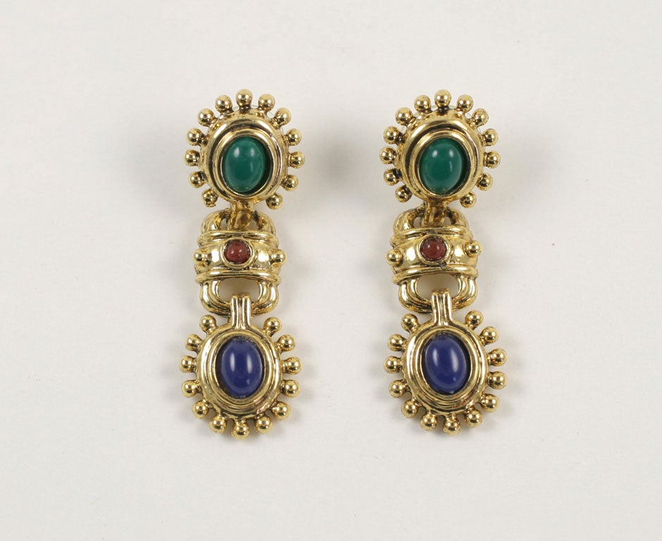 Pierced drop earrings with an green oval cabochon, a blue oval cabochon, and a small red round cabochon in an intricate goldtone setting. There is a hallmark stamp on the back.