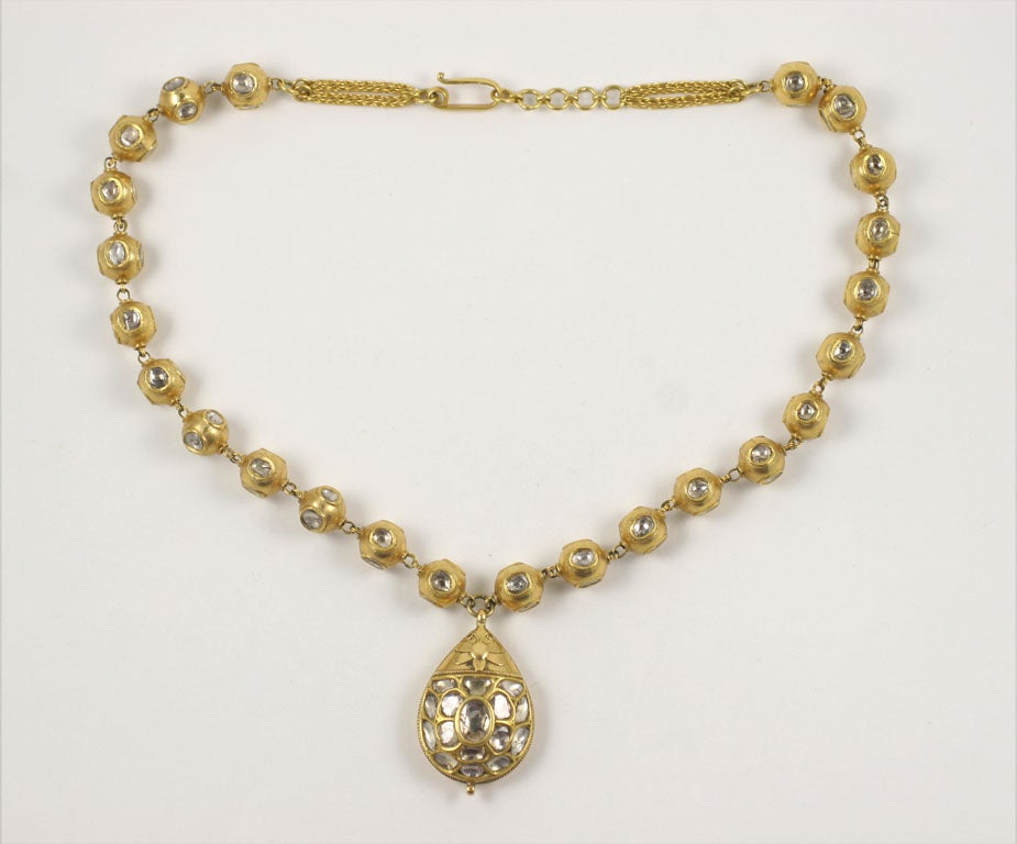 An 18kt yellow gold and rose cut diamond necklace. The necklace is composed of 18kt yellow gold beads set with rose cut diamonds and a tear drop shaped pendant set with rose cut diamonds.