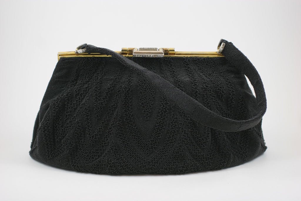 Excuisite black micro-beaded evening bag with rhinestone accents on the clasp and hinges. This bag has a beaded black on black beaded design done in the tiniest beads. The rhinestones in the frame are cut in the style of old mine diamonds.<br
