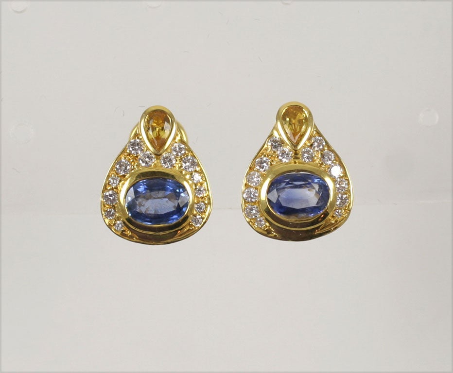 Pair of 14kt Yellow Gold Earrings, each set with an Oval Faceted Ceylon Sapphire surrounded by 14 full cut, clean &  white Diamonds and crowned by a pear shaped faceted Yellow Sapphire.<br />
Marked 585