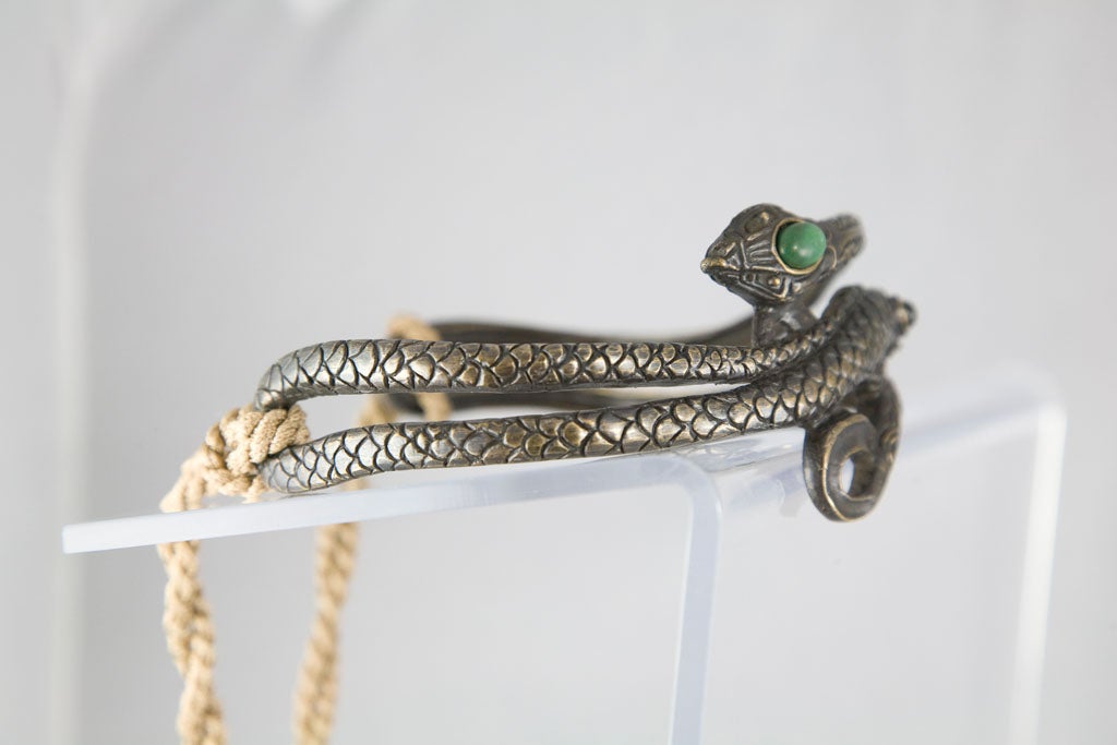 Great cast bronze choker consisting of two entwined snakes set with stones and finished with silk cord and tassels.