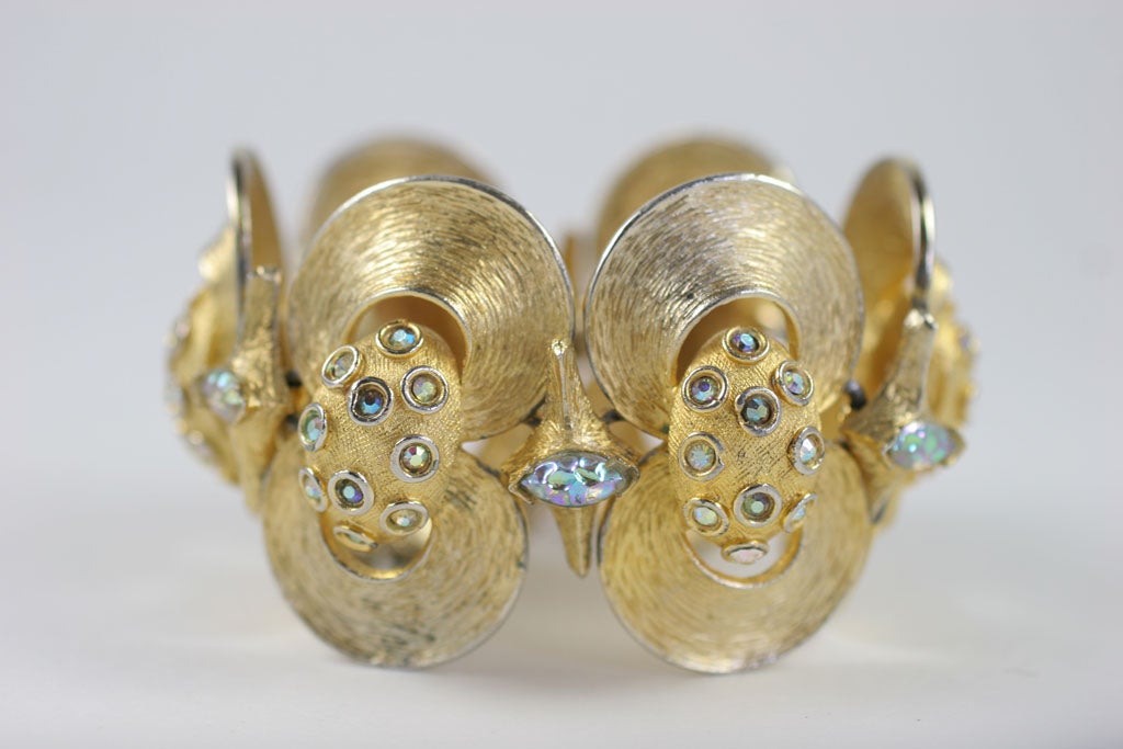 Striated goldtone double clamshell style bracelet with aurora borealis rhinestones.