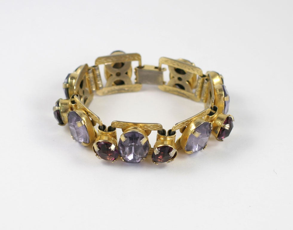 A lovely seven oval cut smokey topaz style stones and six round cut amethyst style stones prong set in a goldtone link bracelet.