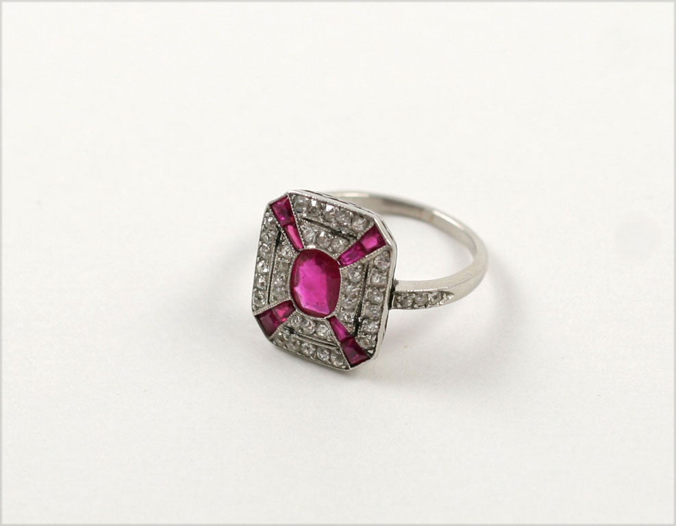 The octagonal ring set in the center with an oval ruby within a border of single-cut diamonds and calibre' cut rubies. ring size 5 3/4. can be sized easily.